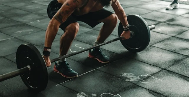 A man setting up to lift a loaded barbell in a gym